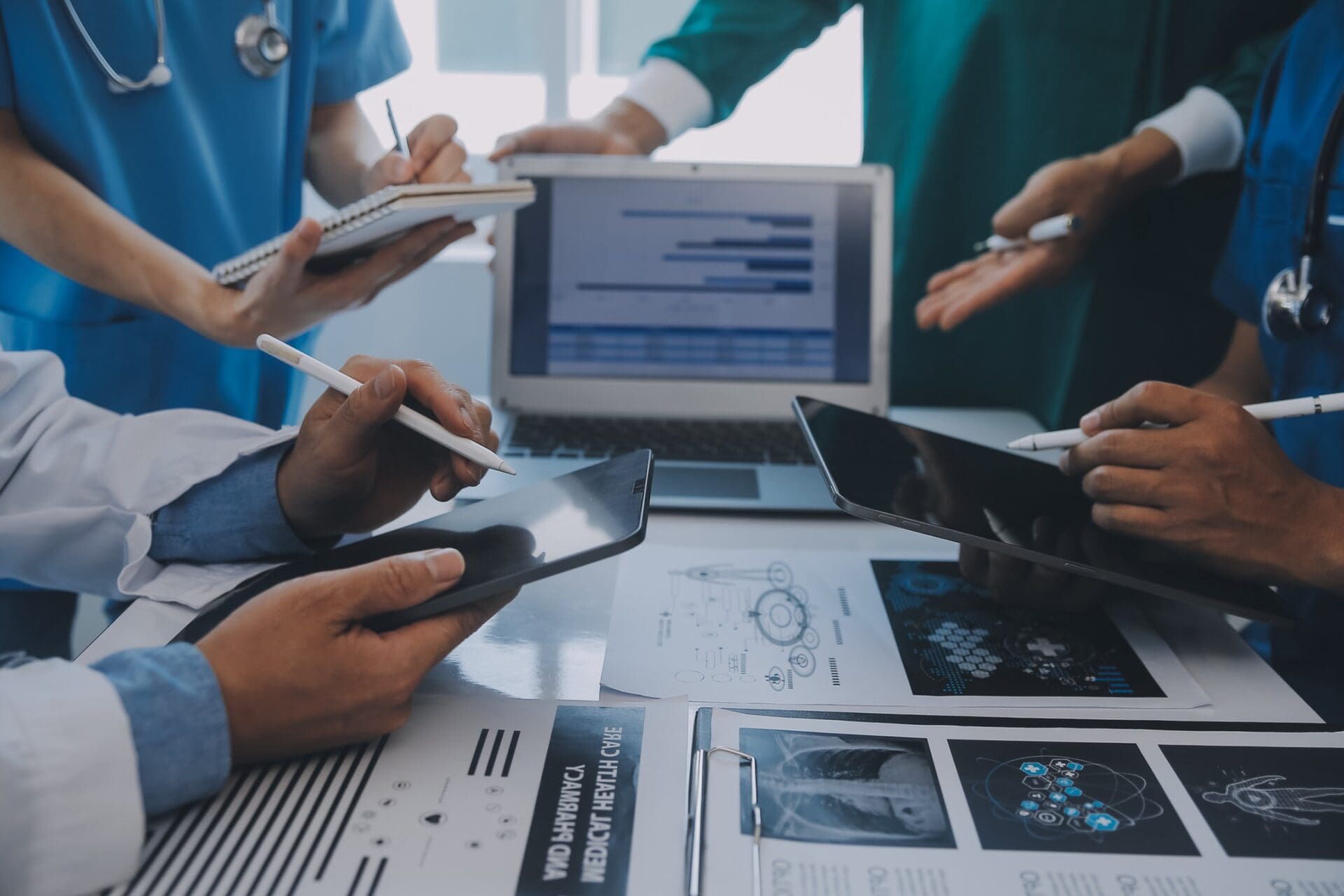 Multiracial team of doctors discussing a patient standing grouped in the foyer looking at a tablet computer